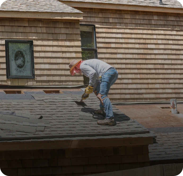 Worker fixing roof with shingles.