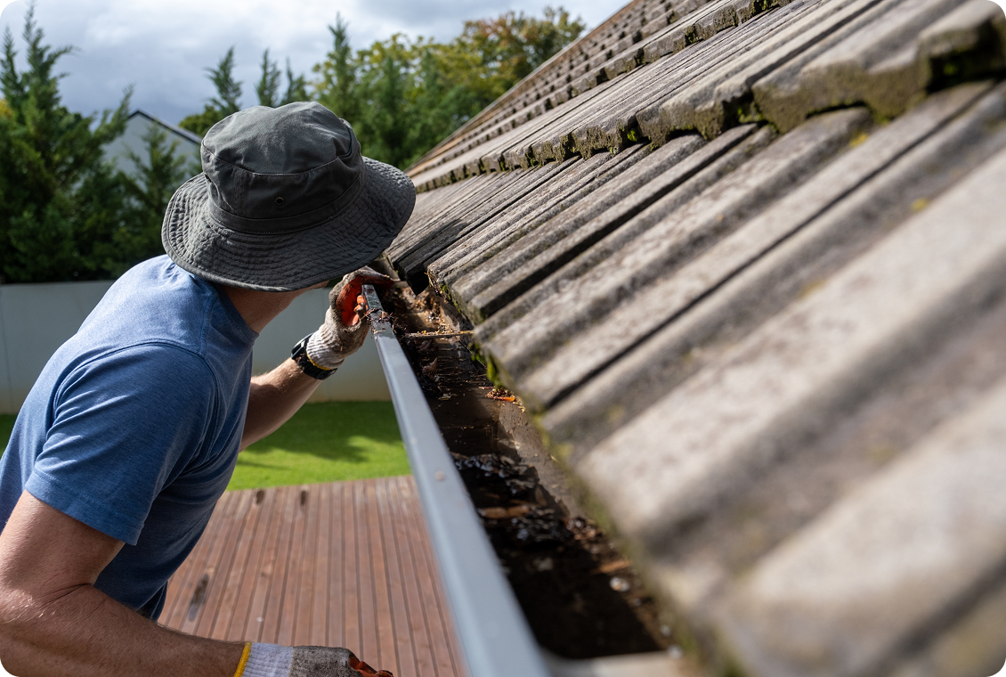 Individual maintaining roof gutter outdoors