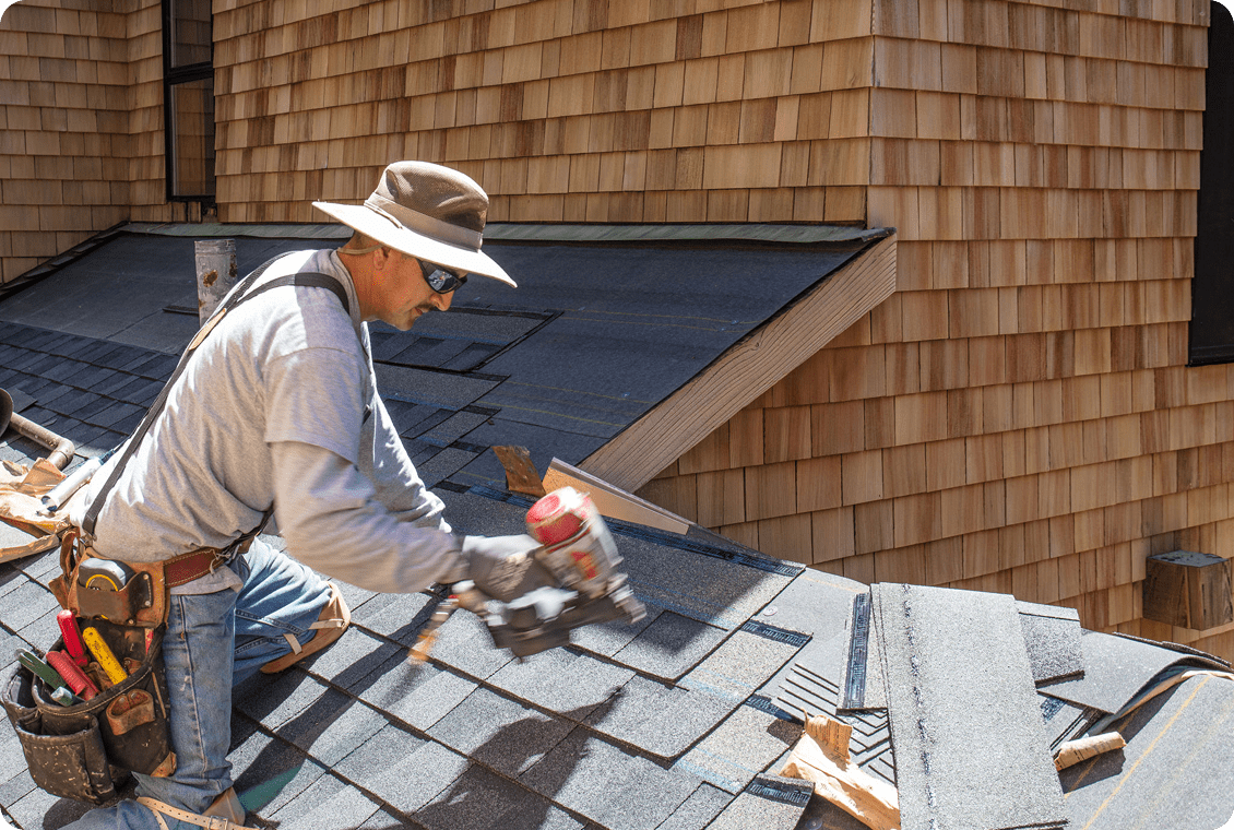 Worker using nail gun on rooftop